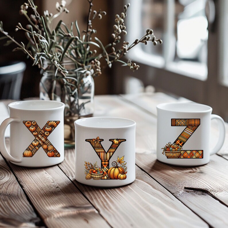 Pode incluir: Tr&ecirc;s canecas de cer&acirc;mica branca com designs de outono. As canecas apresentam as letras X, Y e Z, cada uma decorada com um padr&atilde;o xadrez e folhas de outono e ab&oacute;boras.