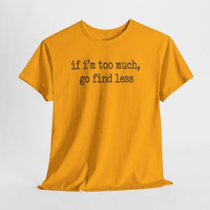 A yellow t-shirt with the text "if i'm too much, go find less" printed on it.