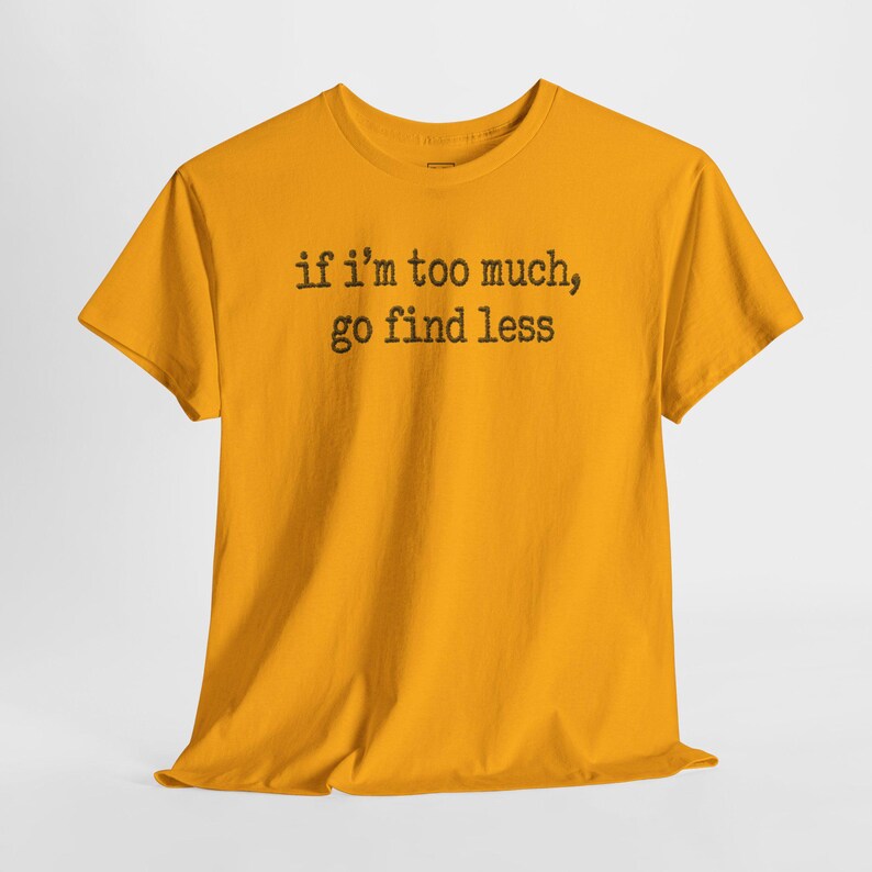 A yellow t-shirt with the text "if i'm too much, go find less" printed on it.