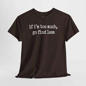 A dark brown t-shirt with the text "if i'm too much, go find less" printed on it.