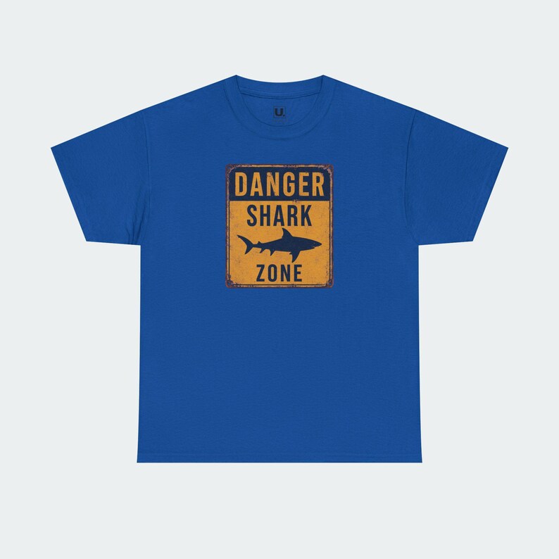 A blue t-shirt with a graphic design that says "DANGER SHARK ZONE" in bold letters.