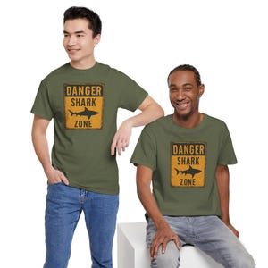 Two young men wearing green t-shirts with a "Danger Shark Zone" warning graphic.