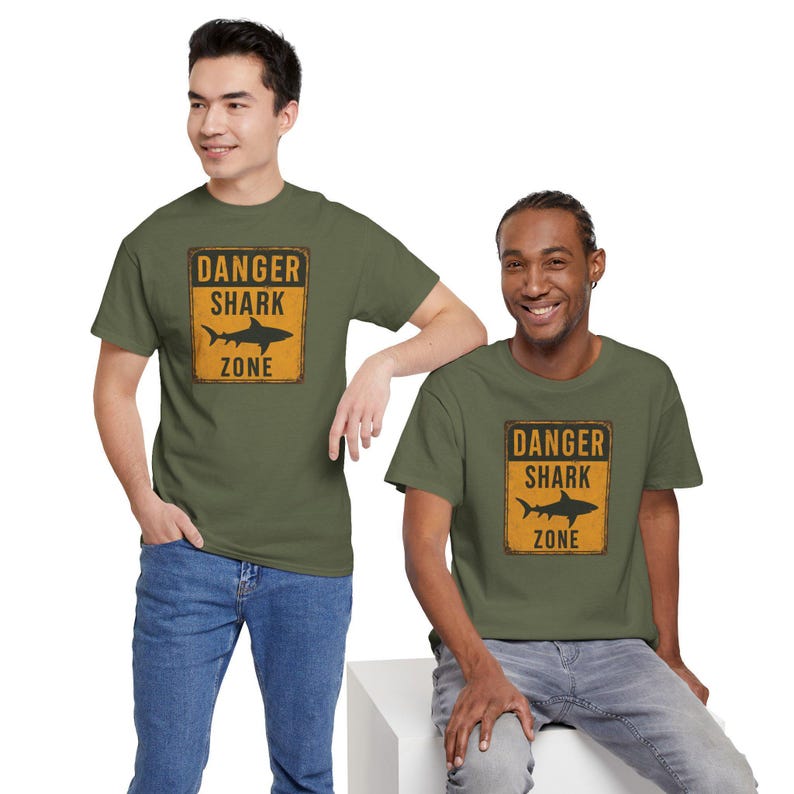 Two young men wearing green t-shirts with a "Danger Shark Zone" warning graphic.