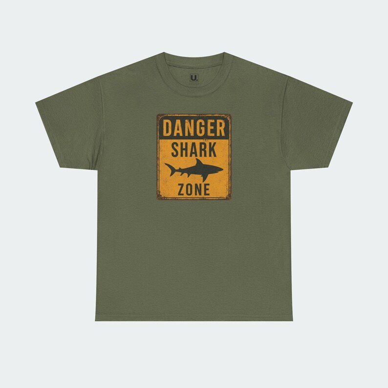 A green t-shirt with a graphic design that says "DANGER SHARK ZONE" in bold letters.