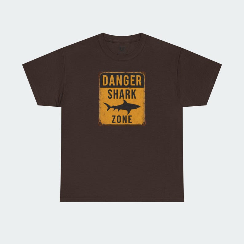 A brown t-shirt with a graphic design that says "DANGER SHARK ZONE" in bold letters.