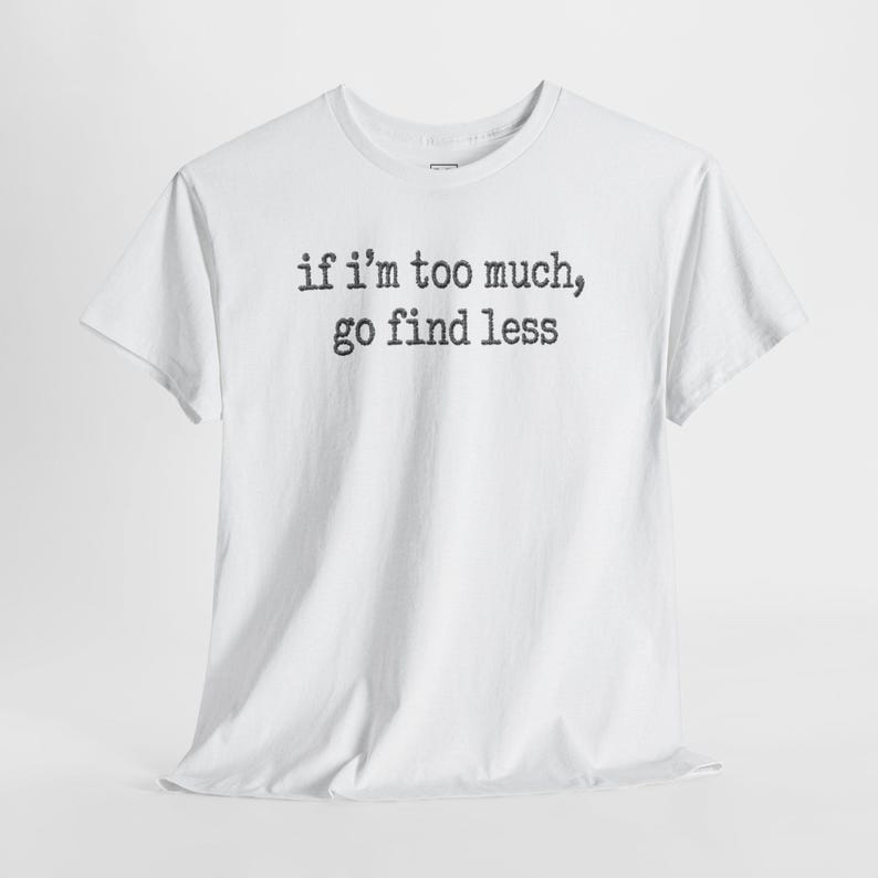 A white t-shirt with the text "if I'M TOO MUCH, go find less" printed on it.
