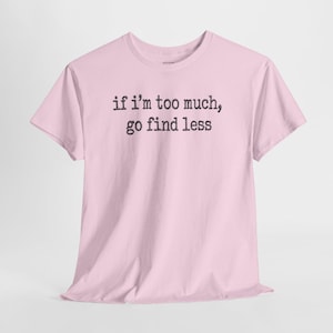 A pink t-shirt with the text "if I'M TOO MUCH, go find less" printed on it.