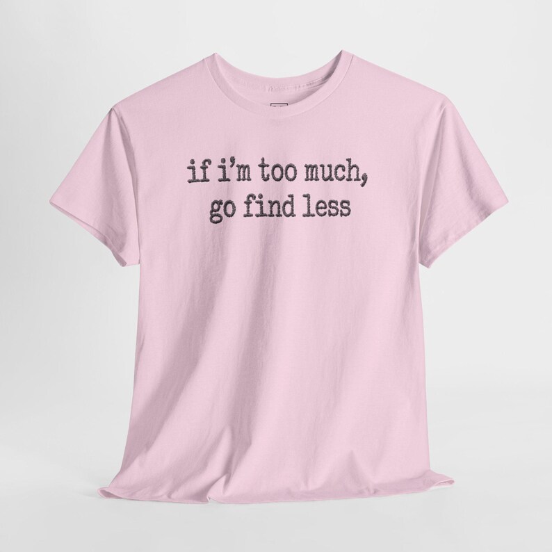 A pink t-shirt with the text "if I'M TOO MUCH, go find less" printed on it.