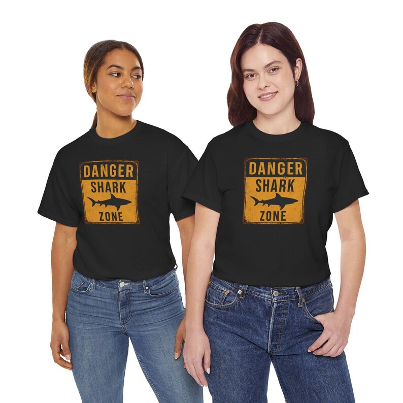 Two women wearing black t-shirts with a yellow and black graphic that says "DANGER SHARK ZONE".