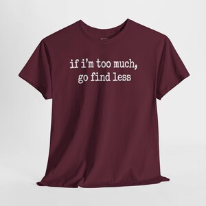 A burgundy-colored t-shirt with the text "if I'M TOO MUCH, go FIND LESS" printed on it.