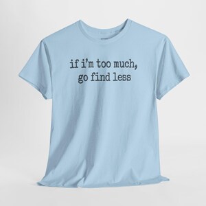 A light blue t-shirt with the text "if I'M TOO MUCH, go find less" printed on it.