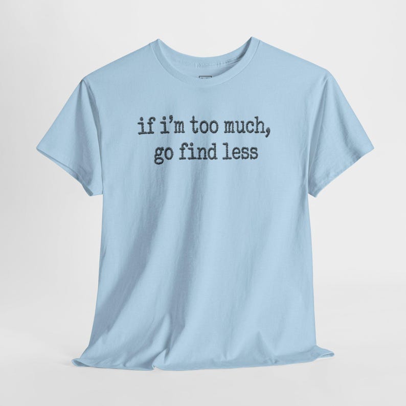 A light blue t-shirt with the text "if I'M TOO MUCH, go find less" printed on it.