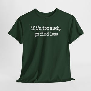 A dark green t-shirt with the text "if i'm too much, go find less" printed on it.