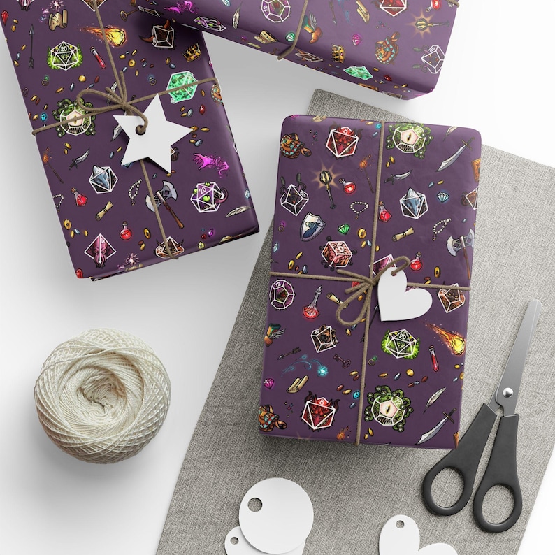 May include: Three wrapped gifts with purple paper featuring a fantasy-themed pattern of dice, potions, and weapons. Each gift is tied with twine and a white tag. A ball of twine, scissors, and blank tags are also present.