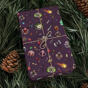 May include: A wrapped gift with a purple background and a repeating pattern of fantasy role-playing game elements. The design includes dice, weapons, potions, and gems. The gift is tied with twine and set against a backdrop of pine needles and pine cones.