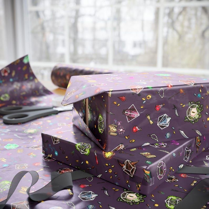 May include: Two gift boxes wrapped in purple paper with a repeating pattern of fantasy-themed illustrations. The boxes are stacked on top of each other. A pair of scissors and a roll of wrapping paper are visible in the background.
