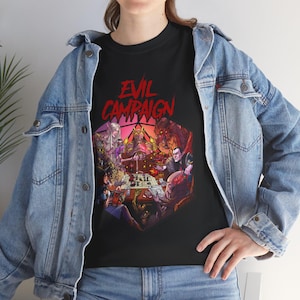 May include: Black t-shirt with a red and white graphic of a Dungeons and Dragons style dice with the text "Evil Campaign" above it. The dice features a group of fantasy characters playing a game.