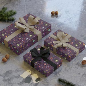 May include: Three wrapped gifts with purple patterned paper and tan or black ribbons. The paper has a repeating pattern of fantasy-themed icons. The gifts are arranged on a gray surface with decorative elements.