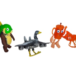 Puede incluir: Una colección caprichosa de figuras hechas a mano. El conjunto incluye una criatura pez verde, un híbrido pato-avión, un personaje de tetera naranja y una figura roja con forma de langosta. Cada figura tiene características y expresiones únicas.
