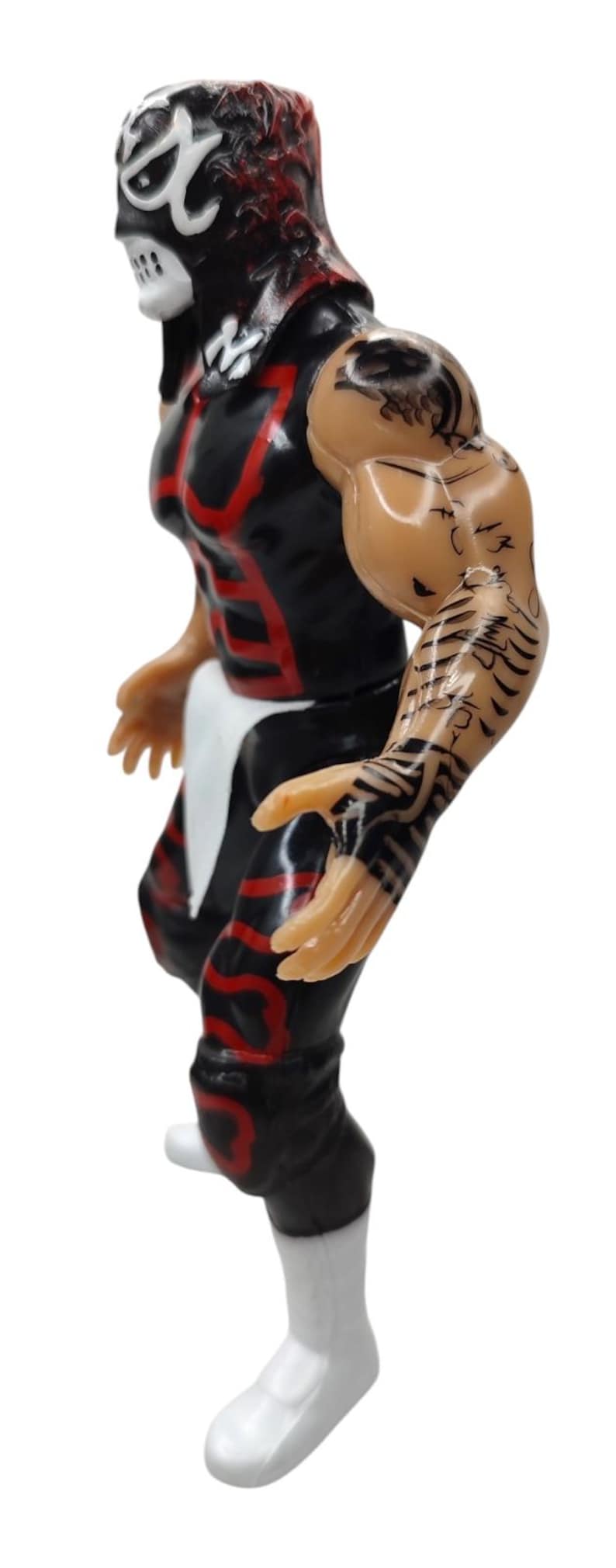 Puede incluir: Figura de acci&oacute;n negra y roja de un luchador enmascarado. La figura tiene tatuajes detallados en el brazo y viste un atuendo negro con detalles rojos. La figura est&aacute; posada en una postura din&aacute;mica, lista para la acci&oacute;n.