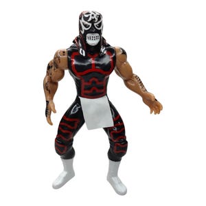 May include: A black and red action figure of a masked wrestler. The figure has a black mask with white accents, a black and red bodysuit, and white boots. The figure is posed with arms outstretched.