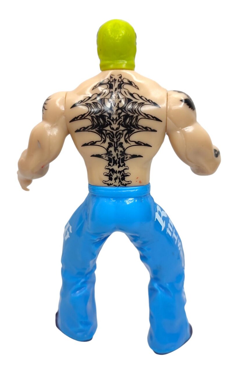 May include: A wrestling action figure with a green mask, black tattoos, and blue pants with white lettering. The figure is posed with its arms outstretched.