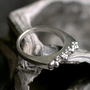 May include: A silver ring with a row of small, round beads along the top edge.
