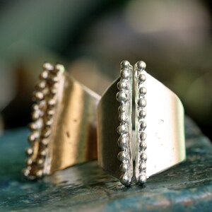 May include: Two silver rings with a textured design. The rings have a row of small beads along the edge.