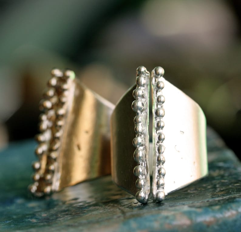 May include: Two silver rings with a textured design. The rings have a row of small beads along the edge.