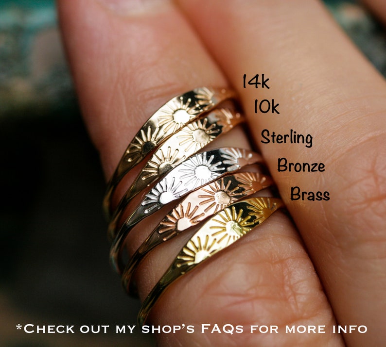 May include: Five stacking rings with a sunburst design. The rings are made of different metals, including 14k gold, 10k gold, sterling silver, bronze, and brass.