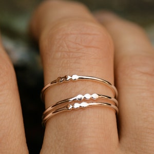 May include: Three delicate gold rings with a row of small, raised dots on each ring.