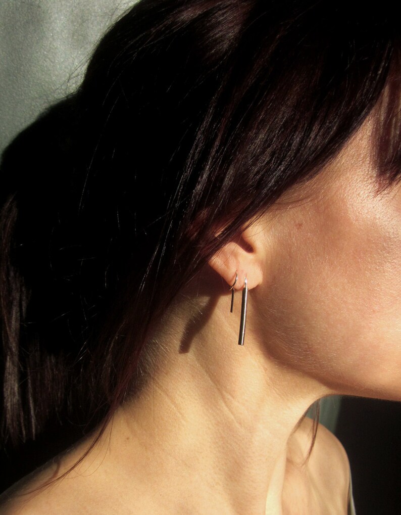 May include: A pair of silver bar earrings with a hoop earring in the other ear.