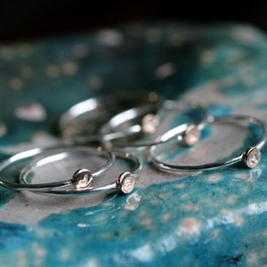 May include: A set of five silver stacking rings with a small circular design on each ring.