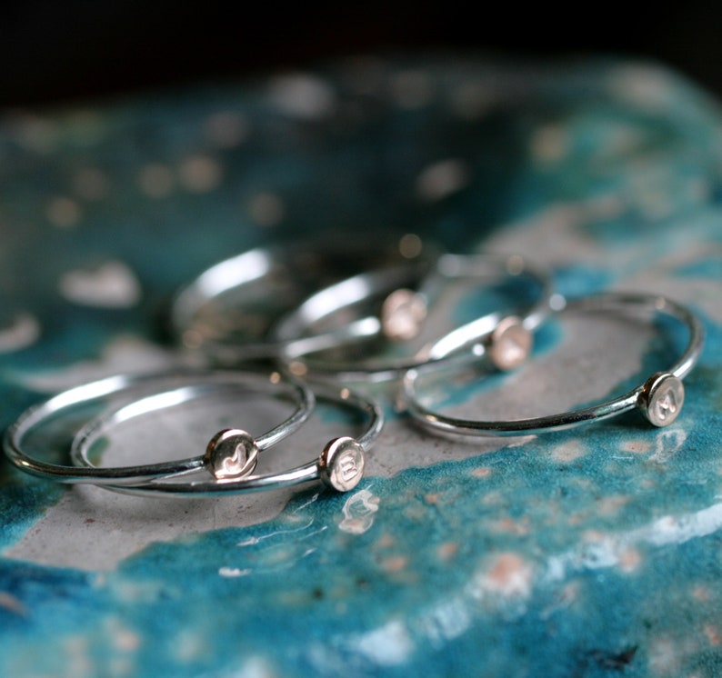 May include: A set of five silver stacking rings with a small circular design on each ring.