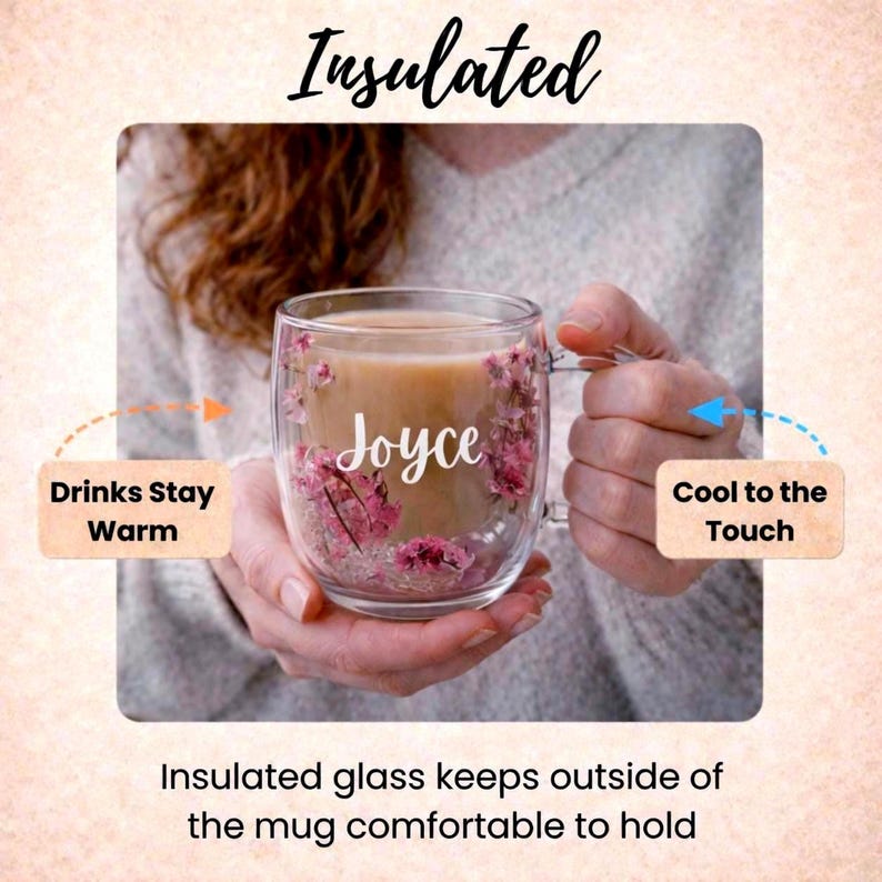 K&ouml;nnte beinhalten: Ein doppelwandiger Glasbecher mit einem beigefarbenen Getr&auml;nk, verziert mit eingebetteten rosa Blumen und dem wei&szlig;en Schriftzug Joyce. Der Becher zeigt oben den Text Insulated sowie Hinweise mit Drinks Stay Warm und Cool to the Touch.