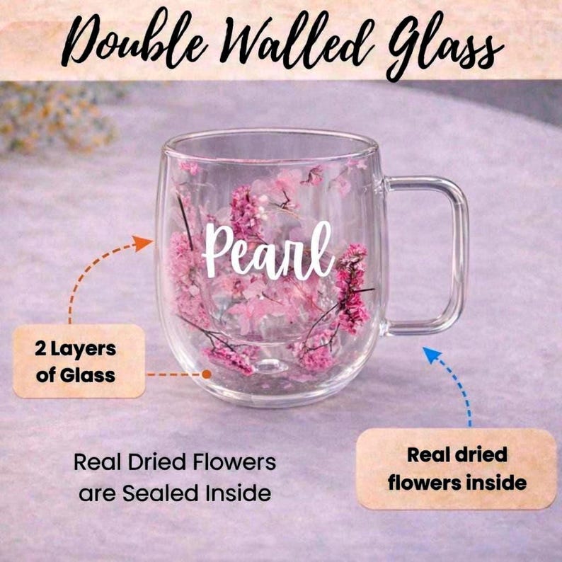 K&ouml;nnte beinhalten: Ein transparenter doppelwandiger Glasbecher mit rosa Trockenblumen, die zwischen den beiden Glasschichten versiegelt sind. Das Wort Pearl ist in wei&szlig;er Schreibschrift aufgedruckt. Textetiketten weisen auf 2 Layers of Glass und Real Dried Flowers hin.
