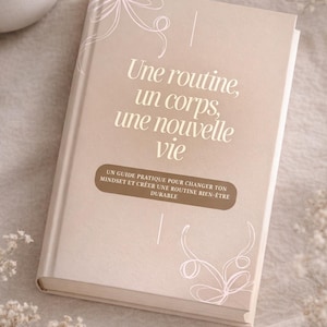 May include: A beige hardcover book with the title "Une routine, un corps, une nouvelle vie" and floral line art. The subtitle reads "Un guide pratique pour changer ton mindset et créer une routine bien-être durable."