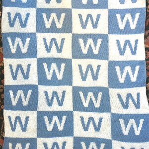 May include: A blue and white knitted blanket with a repeating pattern of the letter 'W'.