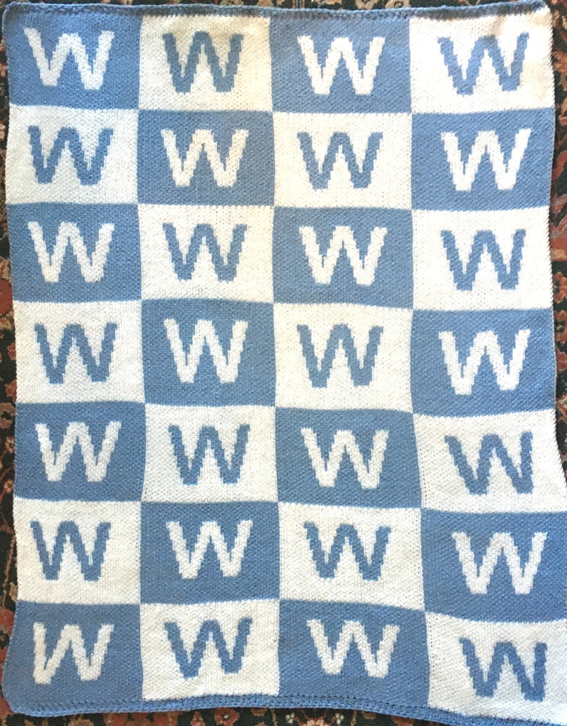 May include: A blue and white knitted blanket with a repeating pattern of the letter 'W'.