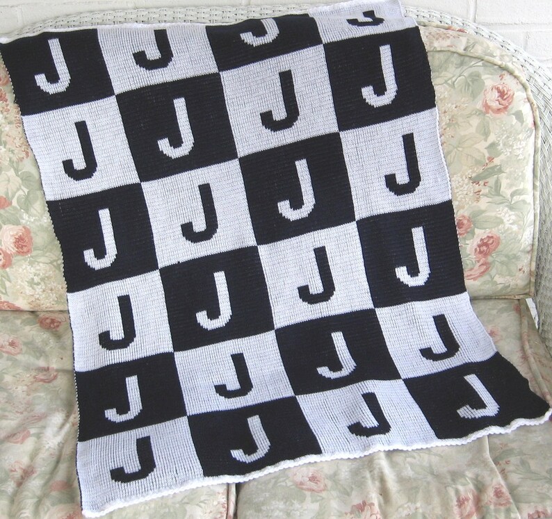 May include: A black and white checkered baby blanket with the letter "J" repeated throughout the design.