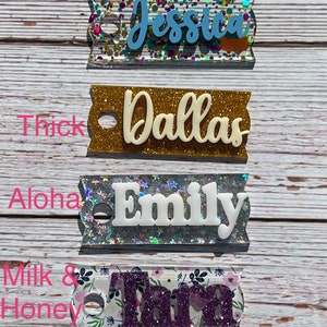 Puede incluir: Cuatro etiquetas de nombre personalizadas con purpurina y diferentes patrones. Los nombres son Jessica, Dallas, Emily y Tara. Las etiquetas son todas rectangulares y tienen un agujero en la parte superior para colgar.