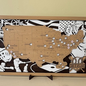 Puede incluir: Mapa de los Estados Unidos con temática de béisbol de madera con bolas de béisbol que marcan ubicaciones. El mapa está enmarcado en madera de color marrón claro, con recortes relacionados con el béisbol en las esquinas. El texto "Casa de Mulligan" es visible.