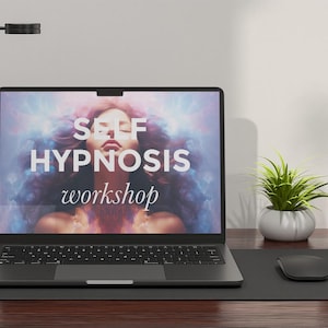 Puede incluir: Un ordenador portátil con una pantalla negra que muestra el texto "SELF HYPNOSIS workshop". La pantalla muestra a una mujer con el pelo largo y oscuro sobre un fondo colorido. El portátil está sobre una alfombrilla de escritorio negra con un ratón negro.