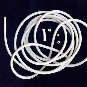 May include: A white silicone tube with three white silicone rings. The tube is coiled and the rings are scattered around it.