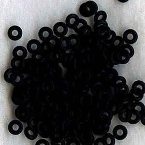 May include: A pile of black rubber rings, also known as jump rings, used for jewelry making.
