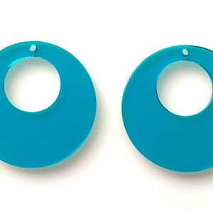 May include: A pair of turquoise blue acrylic earrings with a circular shape and a hole in the center for hanging.