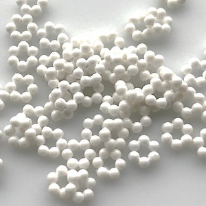May include: White pearl-like flower shaped sprinkles for baking and decorating.