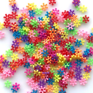 May include: A large pile of colorful plastic star-shaped connectors. The connectors are in various colors, including red, orange, yellow, green, blue, purple, and pink.