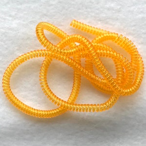 May include: A coiled length of bright yellow plastic cord, often used to organize and protect cords and cables.