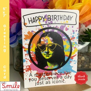 May include: A 5x7 inch greeting card with the text "HAPPY BIRTH DAY". The card features a colorful illustration of the Mona Lisa wearing heart-shaped sunglasses. The card reads "A masterpiece like you deserves a day just as iconic."